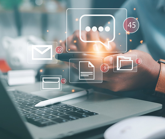 A person uses a laptop displaying a website builder interface, with a smartphone and tablet showing the same website design; green plants are visible at the top corners of the workspace. A person uses a laptop displaying a website builder interface, with a smartphone and tablet showing the same website design; green plants are visible at the top corners of the workspace.