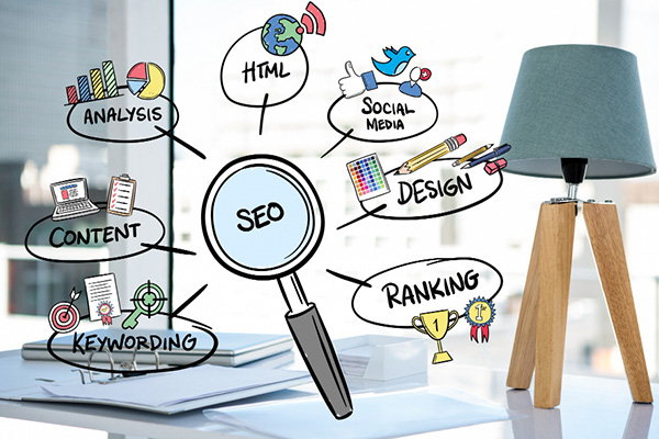 Desk with lamp and papers, overlaid with illustrated SEO mind map showing connections to analysis, HTML, social media, design, ranking, keywording, and content, each with corresponding doodle icons.